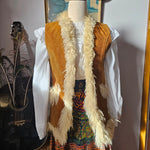 Decorative staff with feathers and patterns on a stand with a guitar in the background