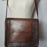 Brown leather handbag with studded detail on a mannequin against a white background