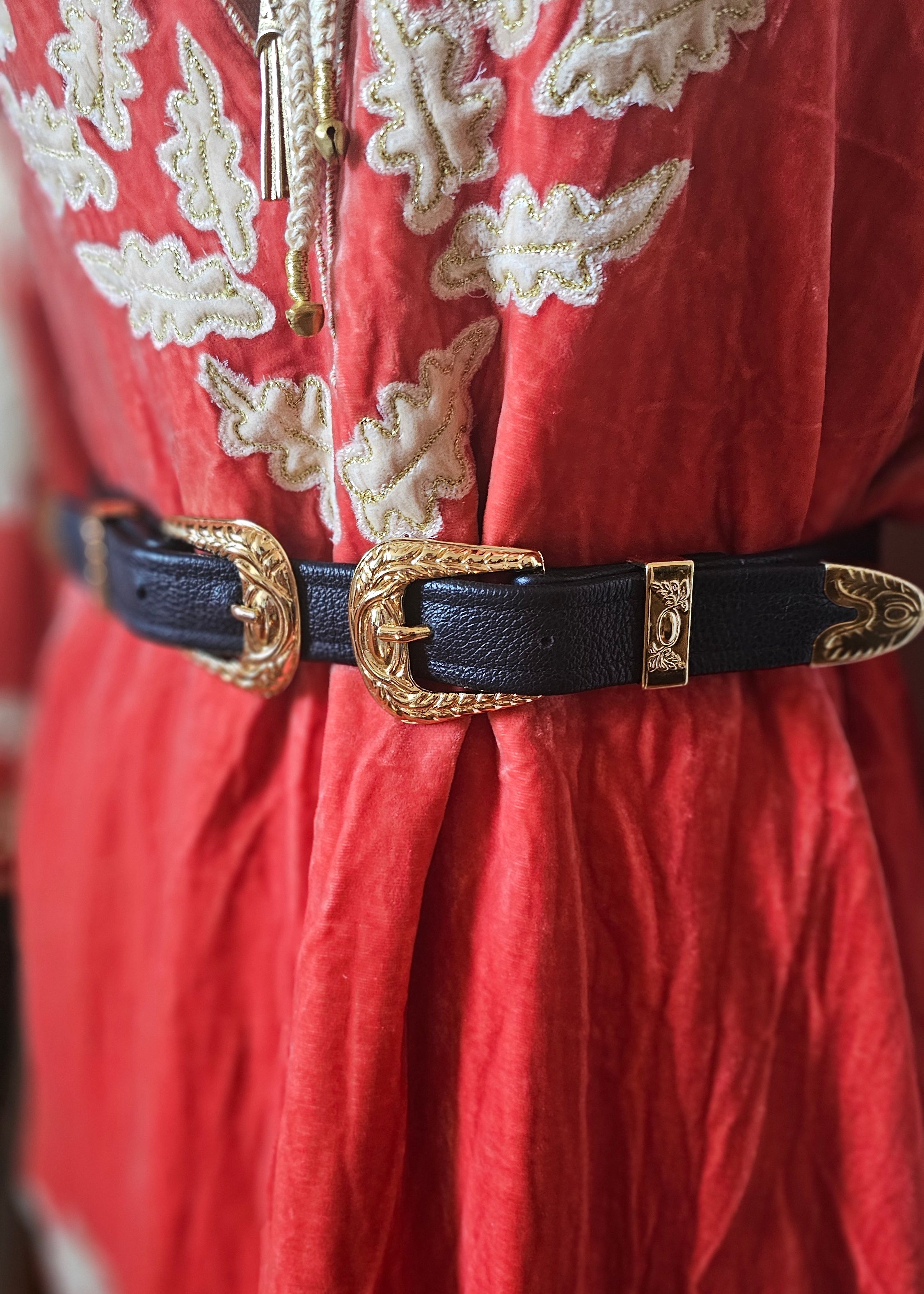 Decorative belt with gold buckle on a red fabric background