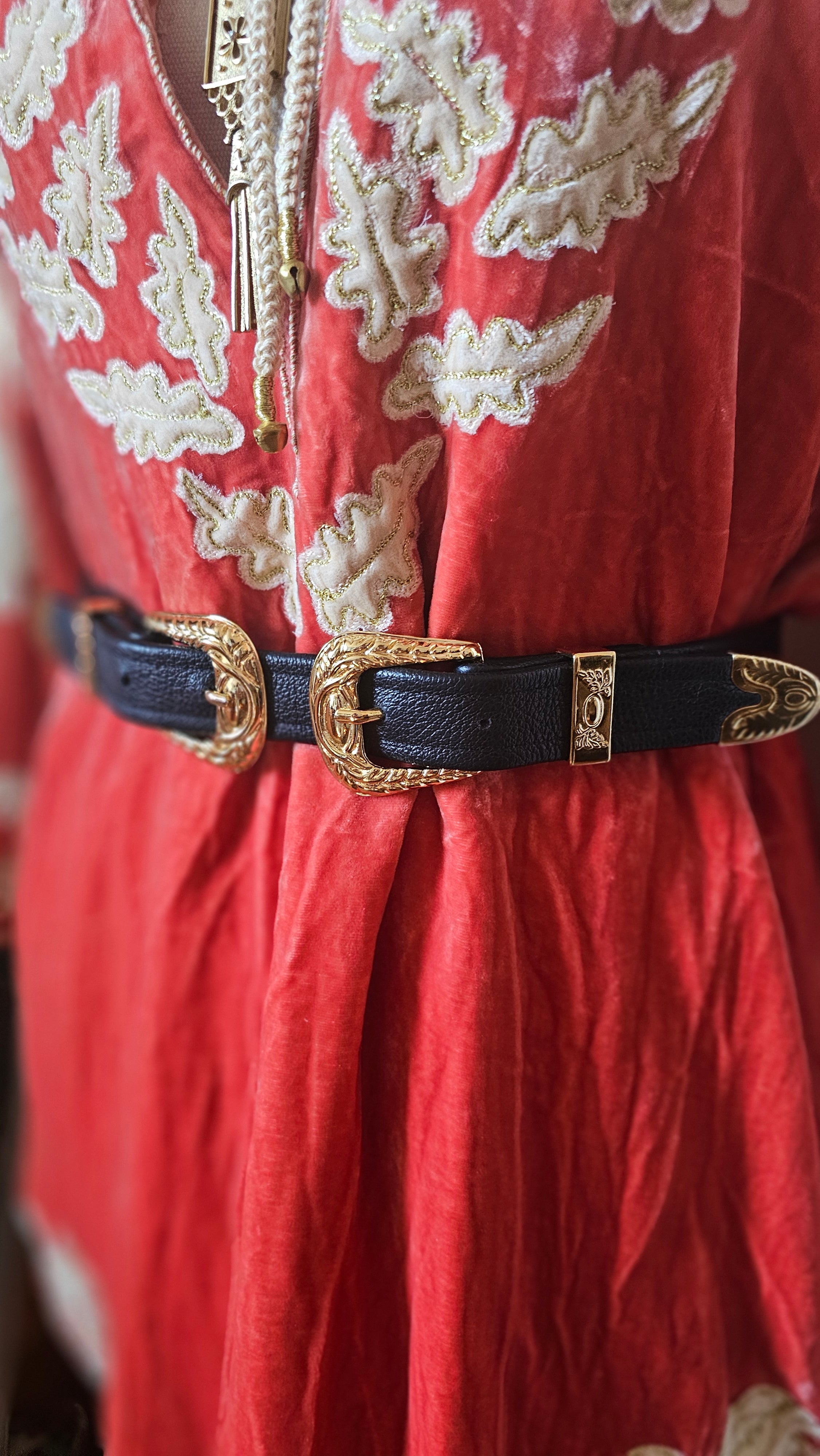 Decorative belt with gold buckle on a red fabric background