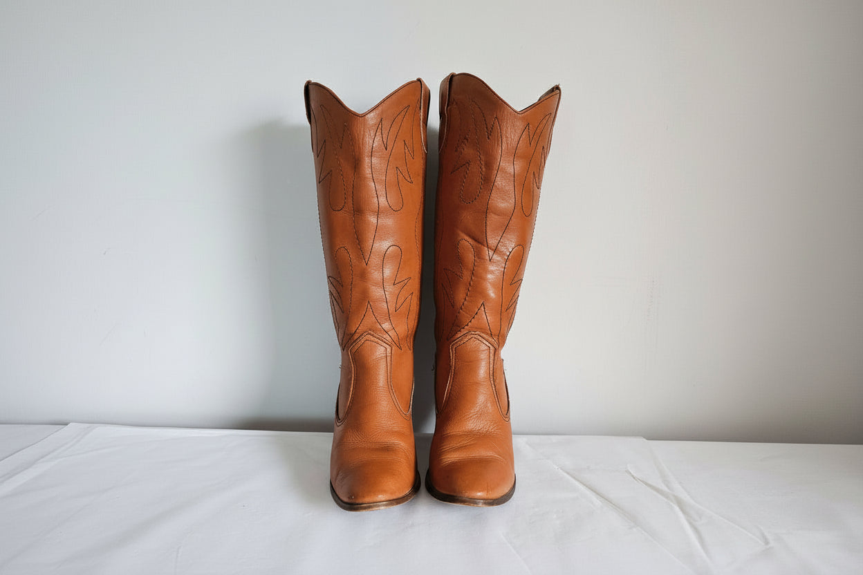 Pair of brown leather boots with embossed design on a white background