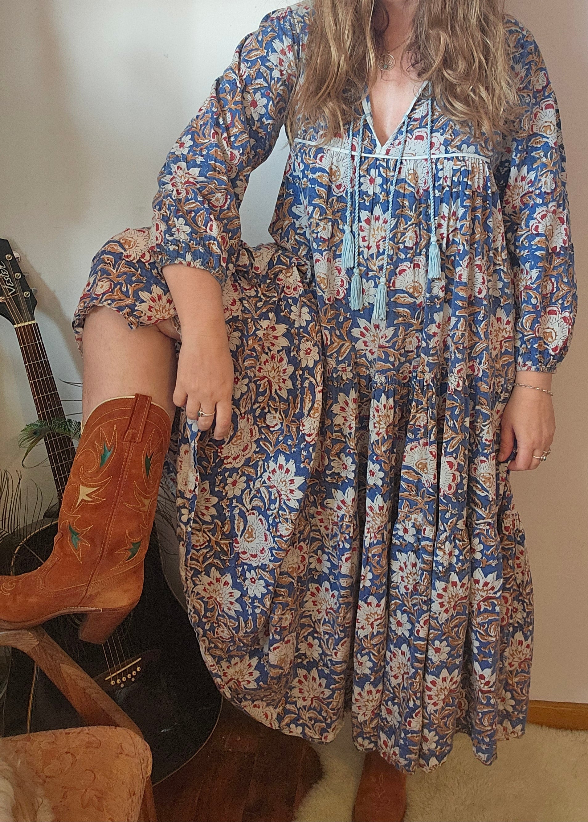 Model wearing Property of Zephyr – Sienna Long Layer Dress in blue and cream paisley print with tassel neckline and balloon sleeves, size small.
