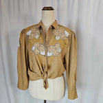 Beige traditional garment with floral embroidery on a mannequin against a plain background