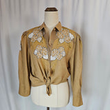 Beige traditional garment with floral embroidery on a mannequin against a plain background