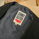 Close-up of a Johnny Dexter label on a black garment with a floral pattern in the background.