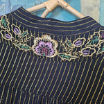 Black fabric with gold embroidery on a textured surface