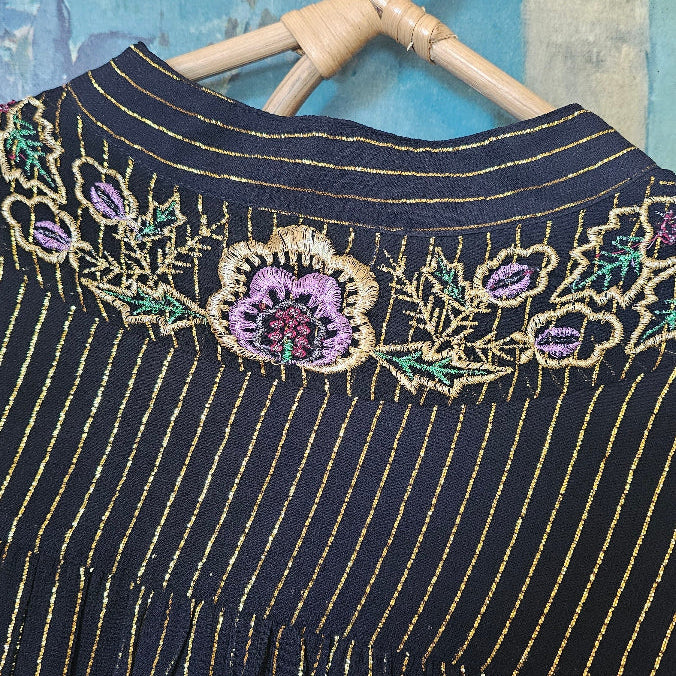 Black fabric with gold embroidery on a textured surface