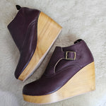 Pair of purple shoes with wooden soles on a white fur surface