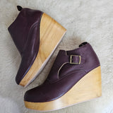 Pair of purple shoes with wooden soles on a white fur surface