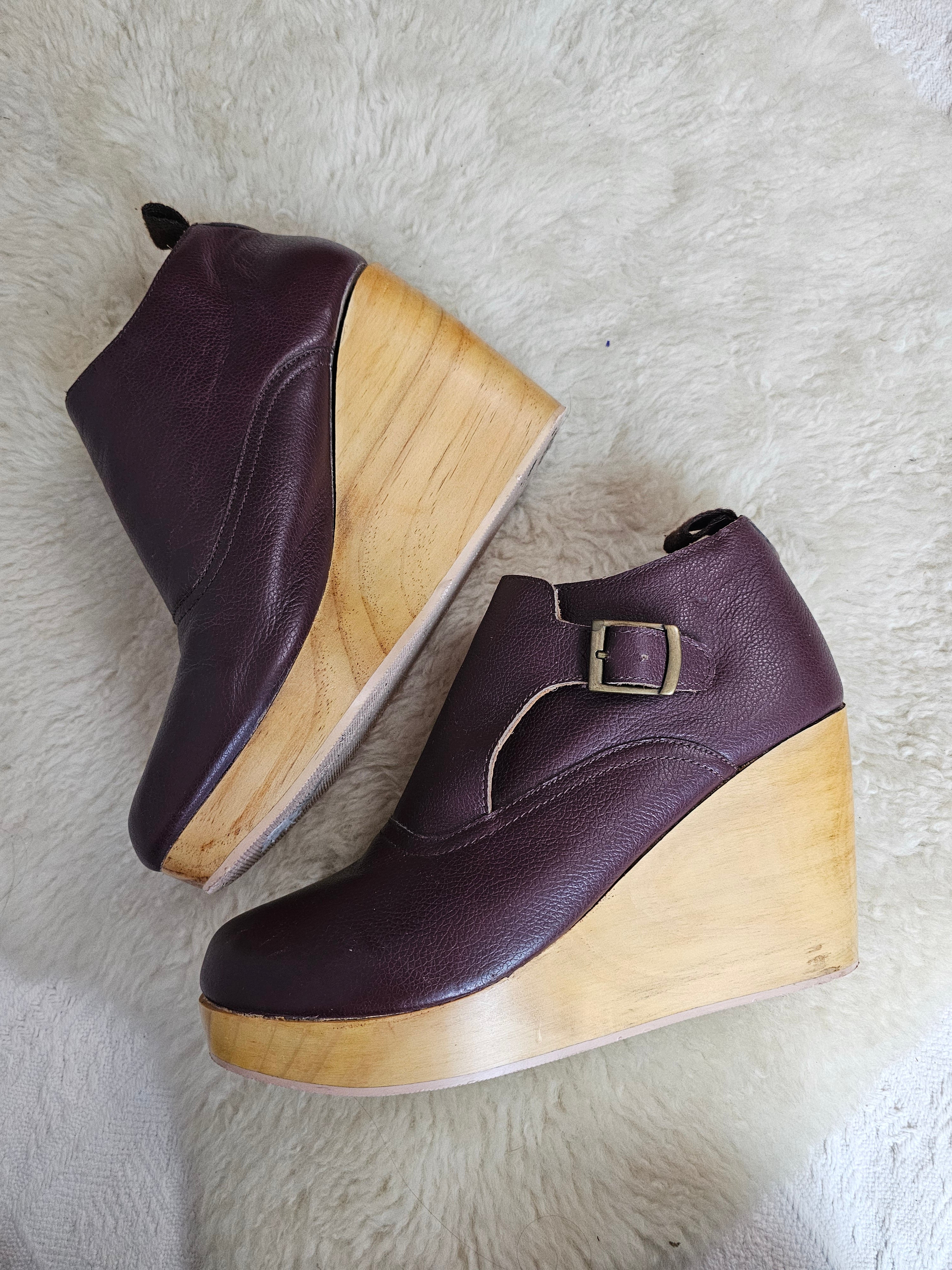 Pair of purple shoes with wooden soles on a white fur surface
