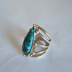 Silver ring with a turquoise stone on a light gray background