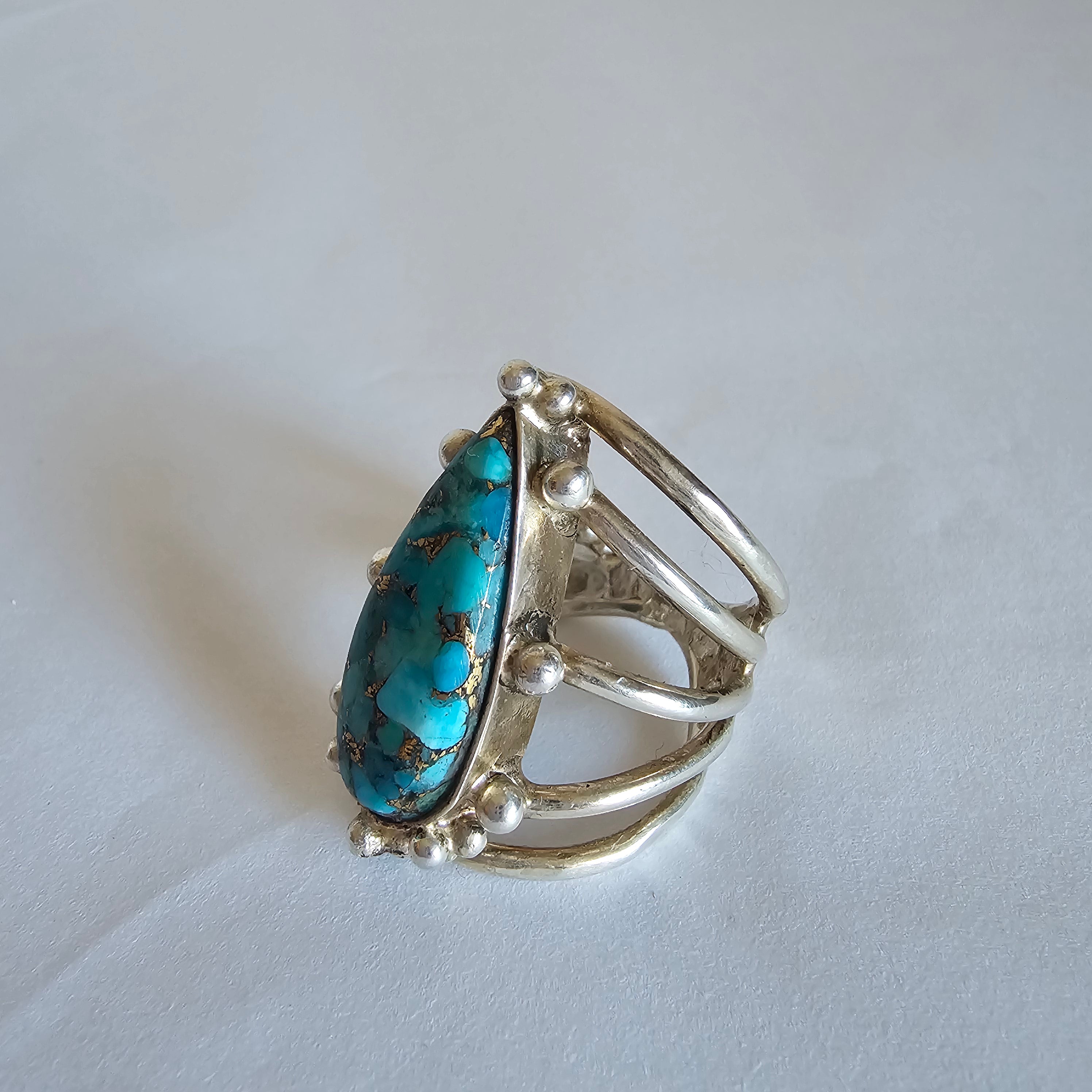Silver ring with a turquoise stone on a light gray background
