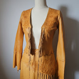 Brown leather outfit with fringes on a mannequin against a plain background