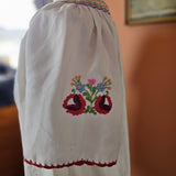 Embroidered sleeve with floral design on a white garment, blurred background