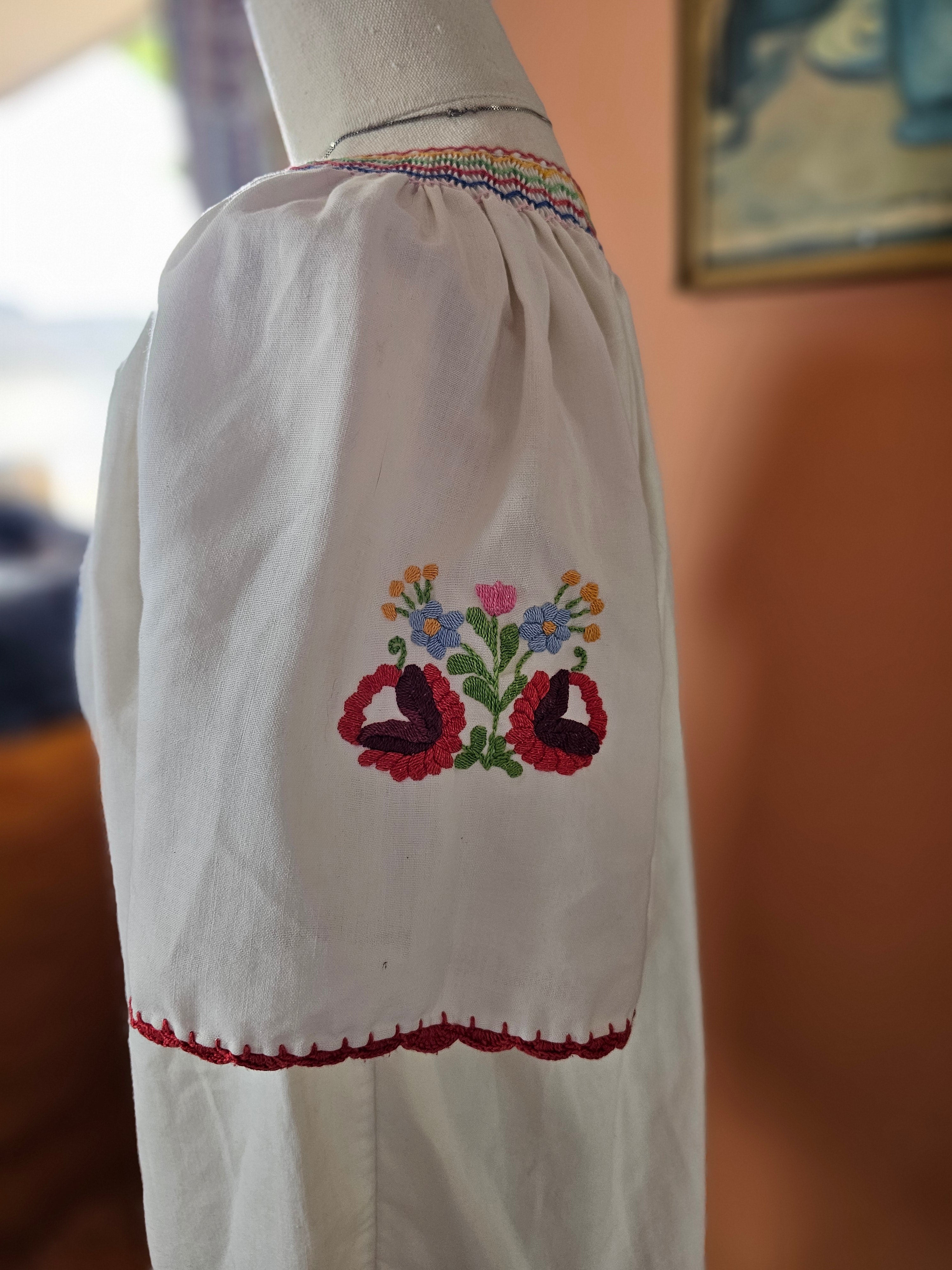 Embroidered sleeve with floral design on a white garment, blurred background