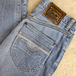 Close-up of a folded pair of blue jeans with a brand label on a beige surface