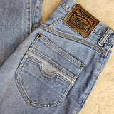 Close-up of a folded pair of blue jeans with a brand label on a beige surface