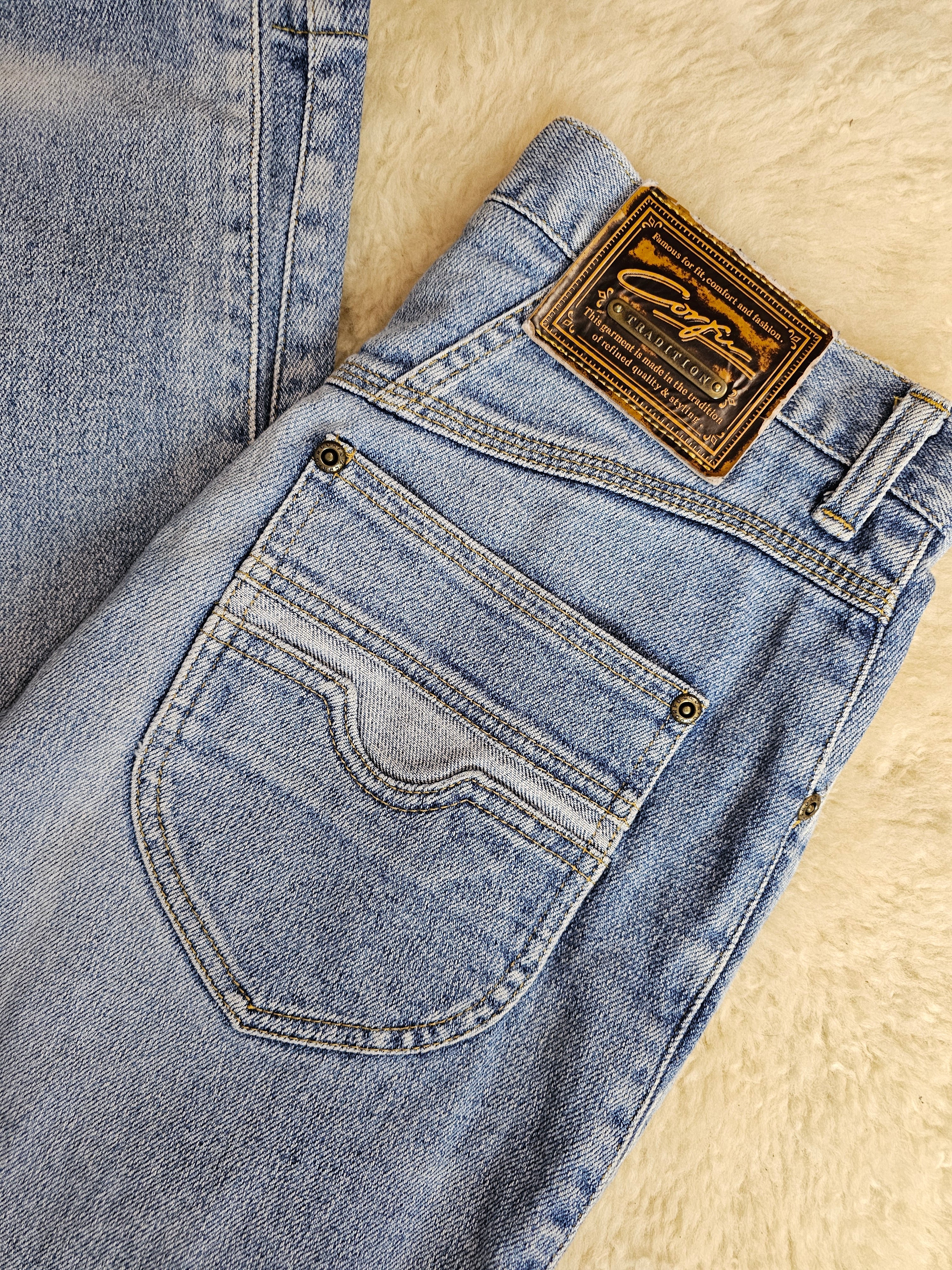 Close-up of a folded pair of blue jeans with a brand label on a beige surface