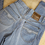 Pair of blue jeans with a brand logo on a wooden surface