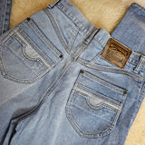Pair of blue jeans with a brand logo on a wooden surface