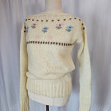 Knitted beige sweater with decorative patterns on a white background