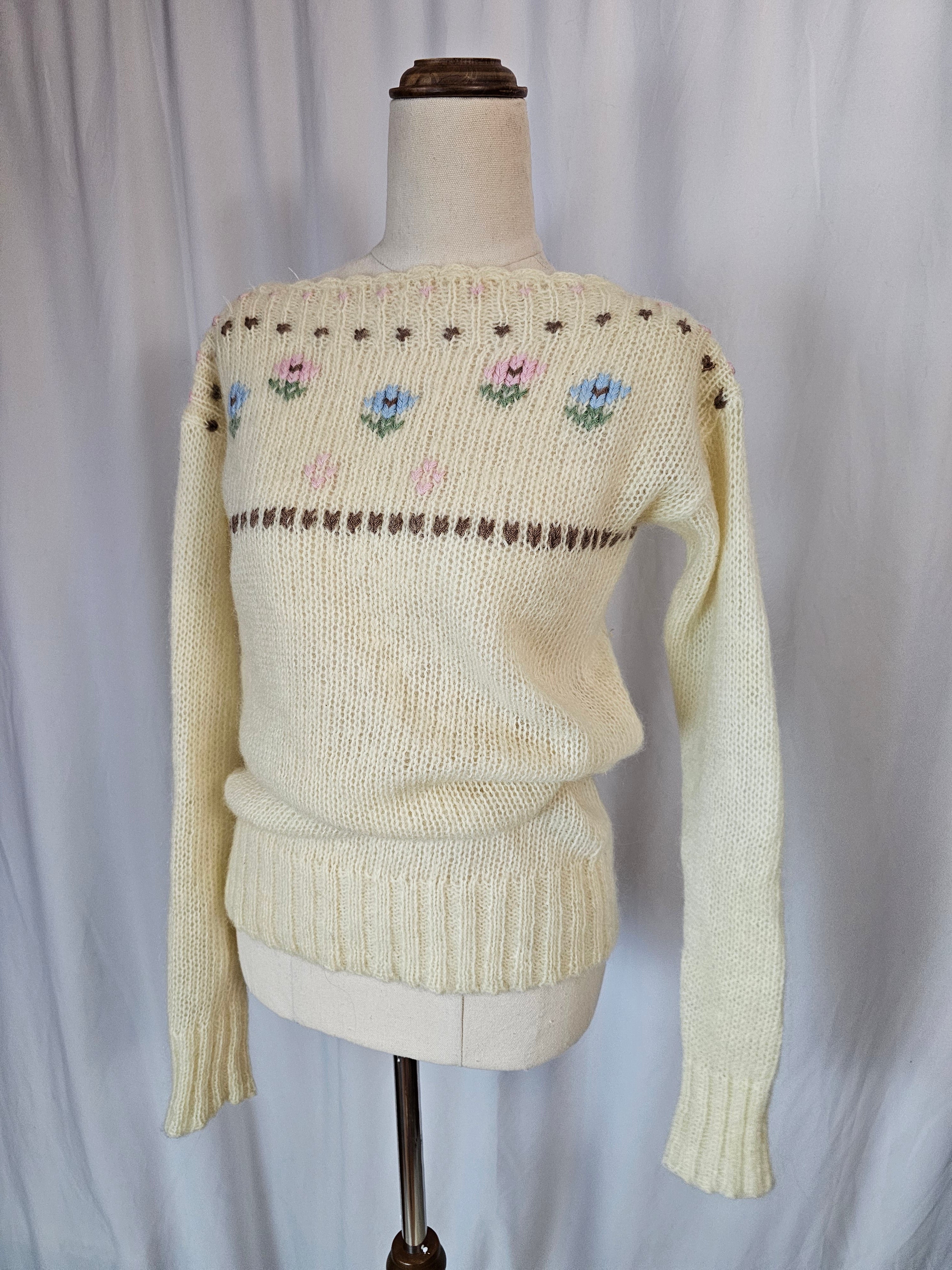Knitted beige sweater with decorative patterns on a white background