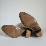 Brown leather shoes with wooden soles on a white surface