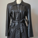 A black leather jacket with a matching tie belt, displayed on a mannequin torso. The jacket features a pointed collar, button closures, and front patch pockets, photographed against a neutral indoor background.
