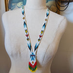 Mannequin head with a colorful beaded headband on a neutral background