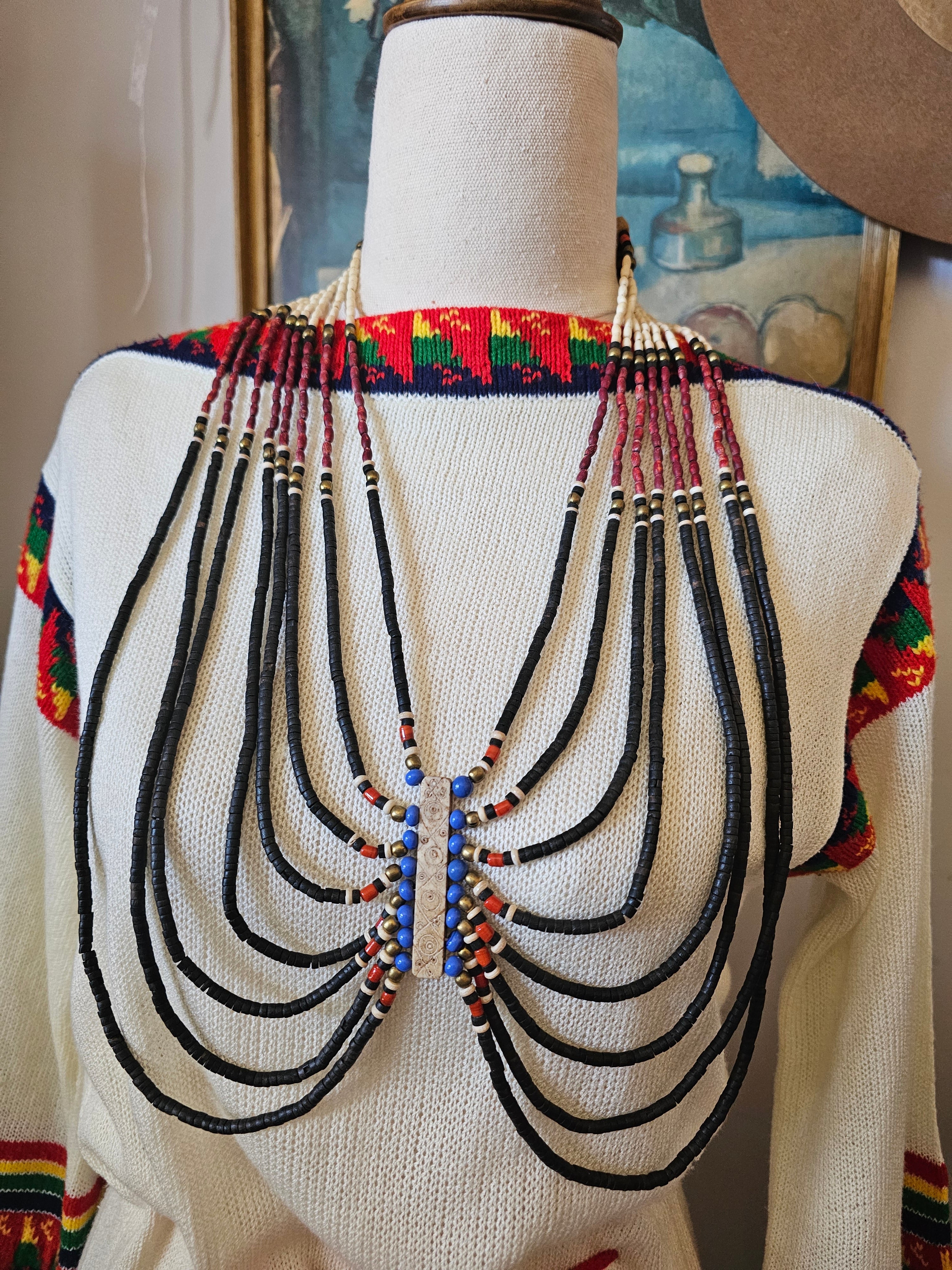 Traditional beaded necklace on a mannequin with a colorful background