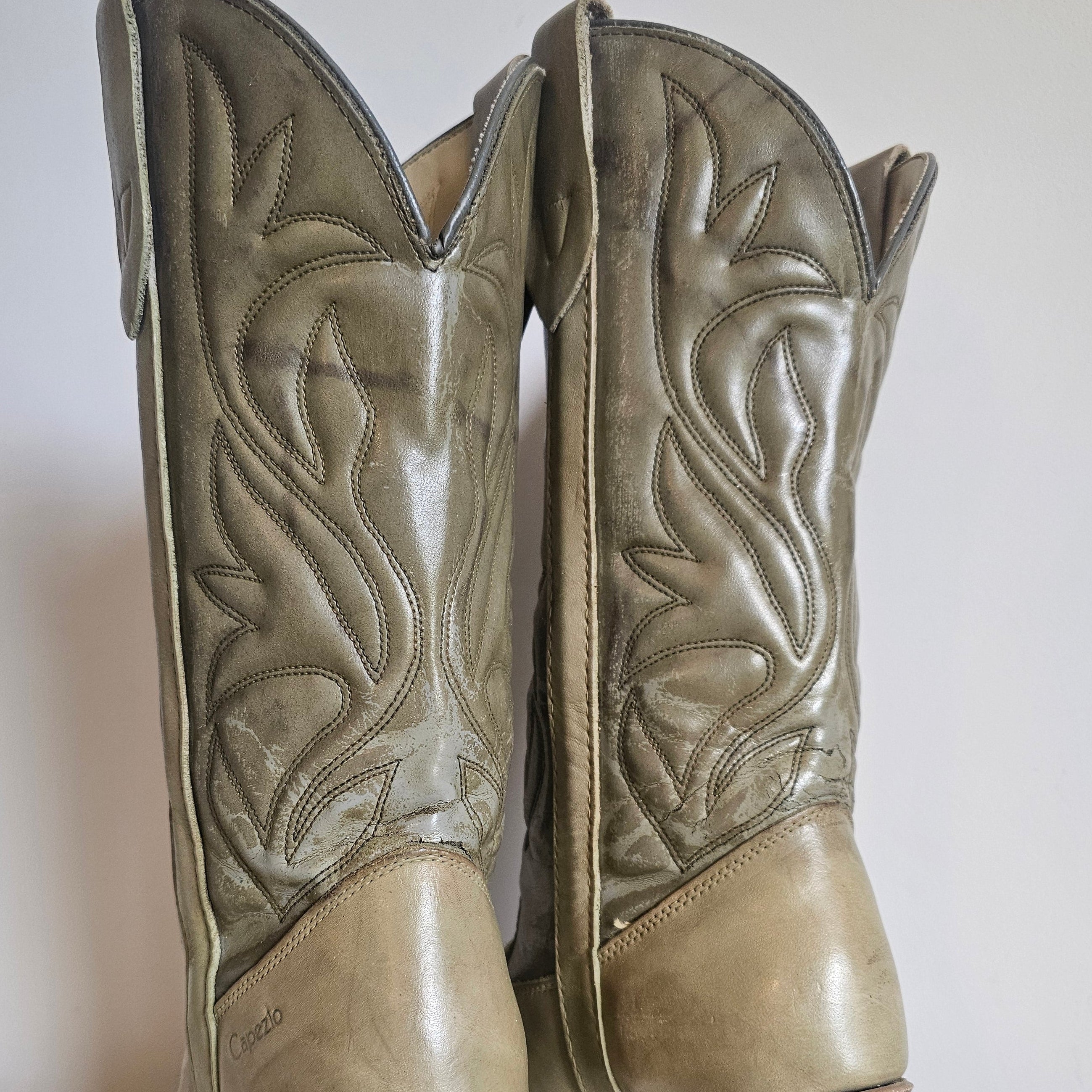 Pair of leather boot-shaped ottomans with intricate designs on a white background.