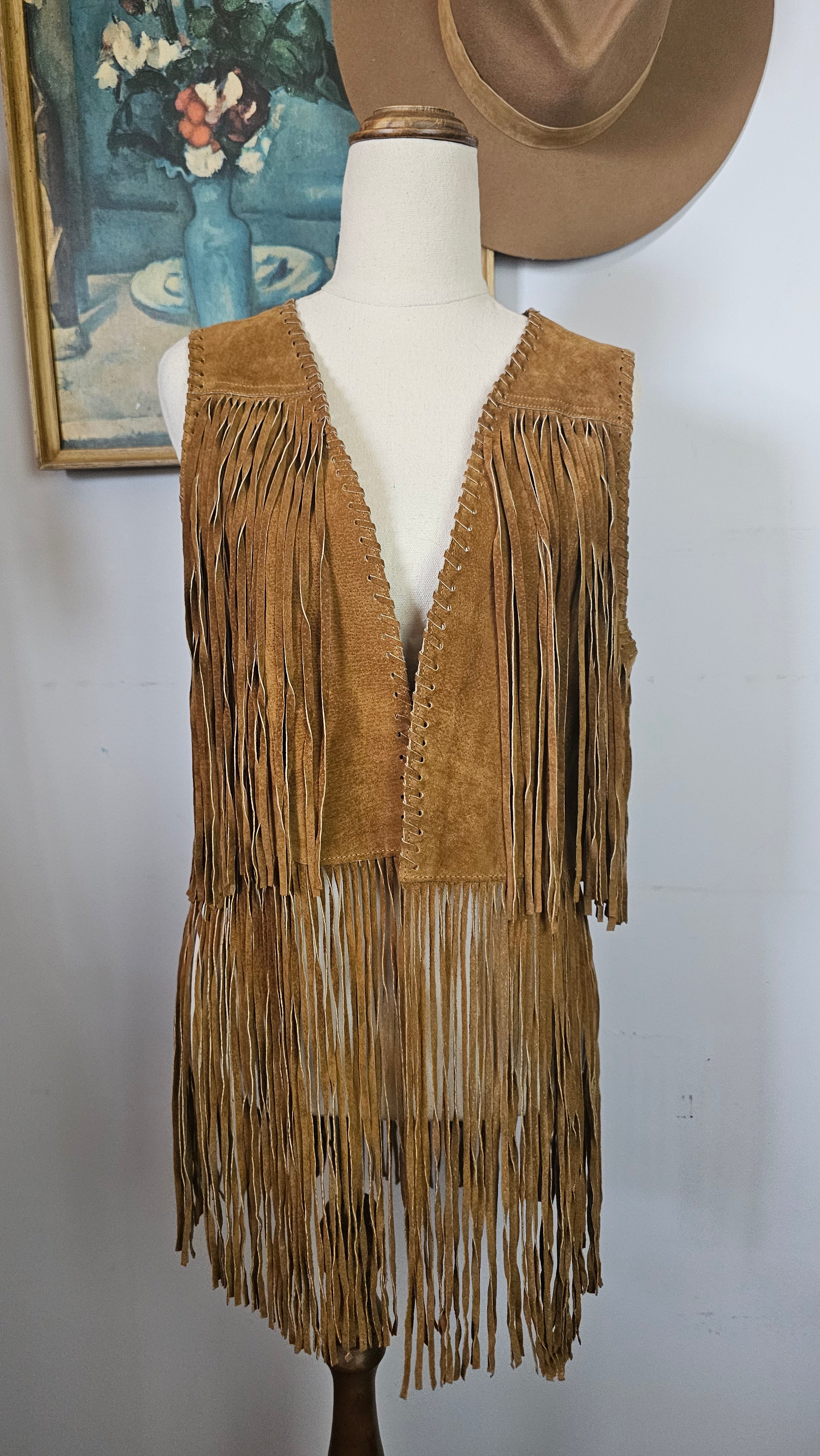 Brown fringed jacket on a mannequin with a plain background