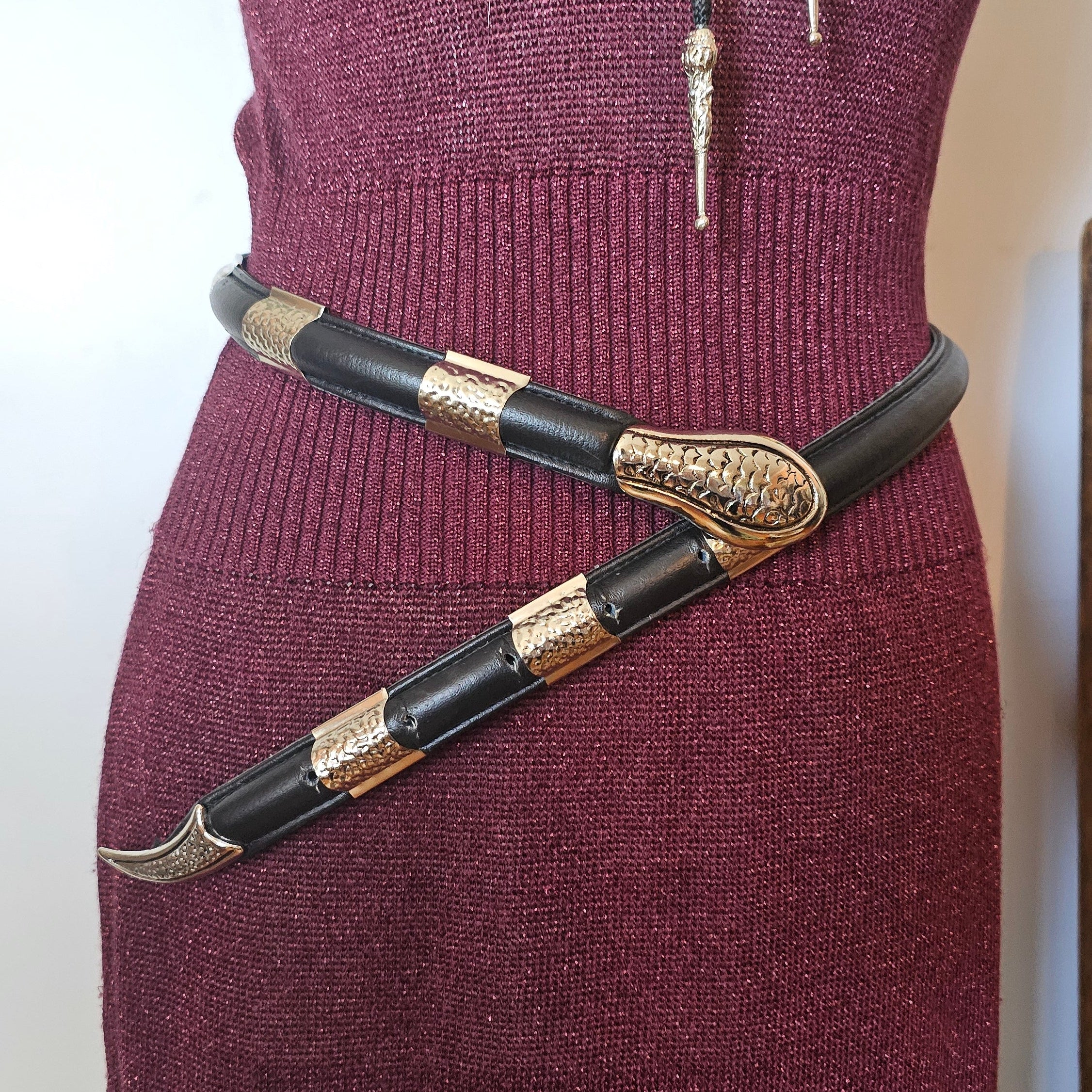 Maroon glove with decorative black and gold strap on a white background