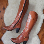 Brown knee-high boots on a white fur rug with wooden floor background