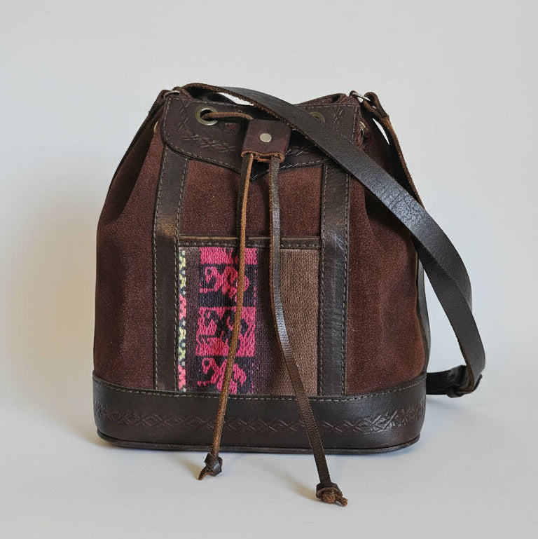 Brown leather bag with colorful patterned flap on a textured surface