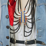 Close-up of a decorated boot with intricate patterns and a red ribbon, worn with blue jeans.