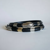 Black leather bracelet with silver clasp on a textured surface
