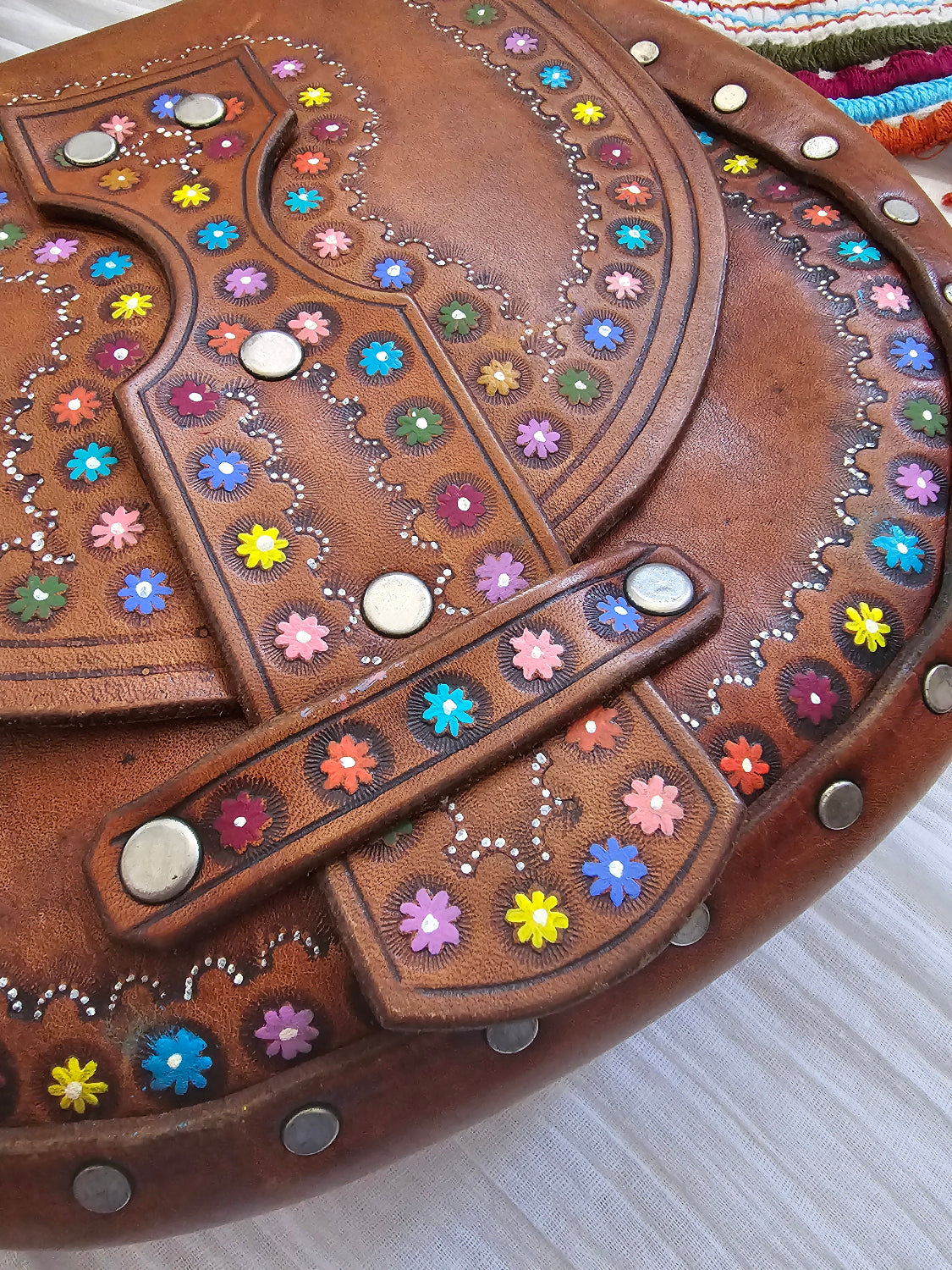 Decorative brown leather item with colorful gemstones on a textured surface