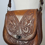Brown leather wallet with intricate embossed designs on a white background