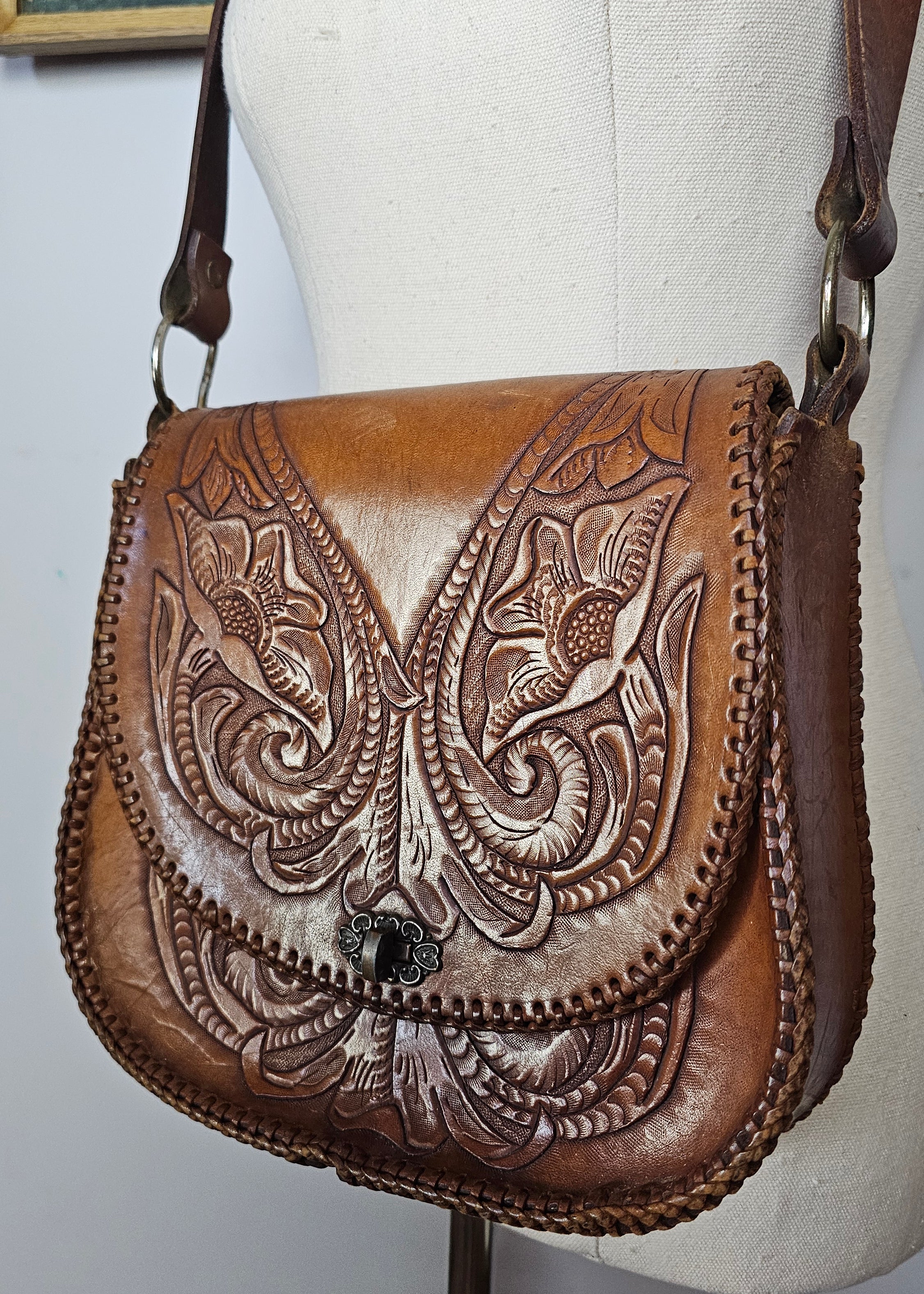 Brown leather wallet with intricate embossed designs on a white background