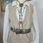 Mannequin wearing a traditional outfit with a hat and decorative sash on a plain background