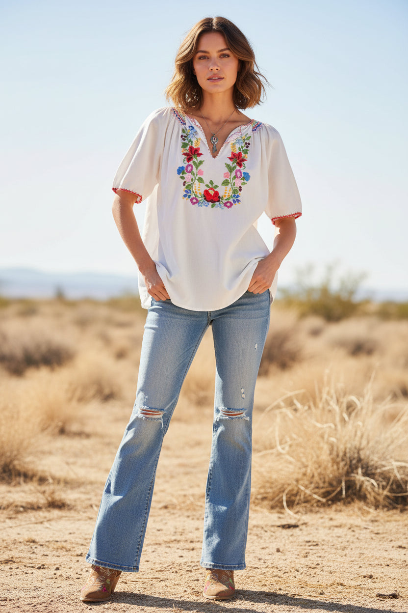White blouse with floral embroidery on a mannequin against a neutral background