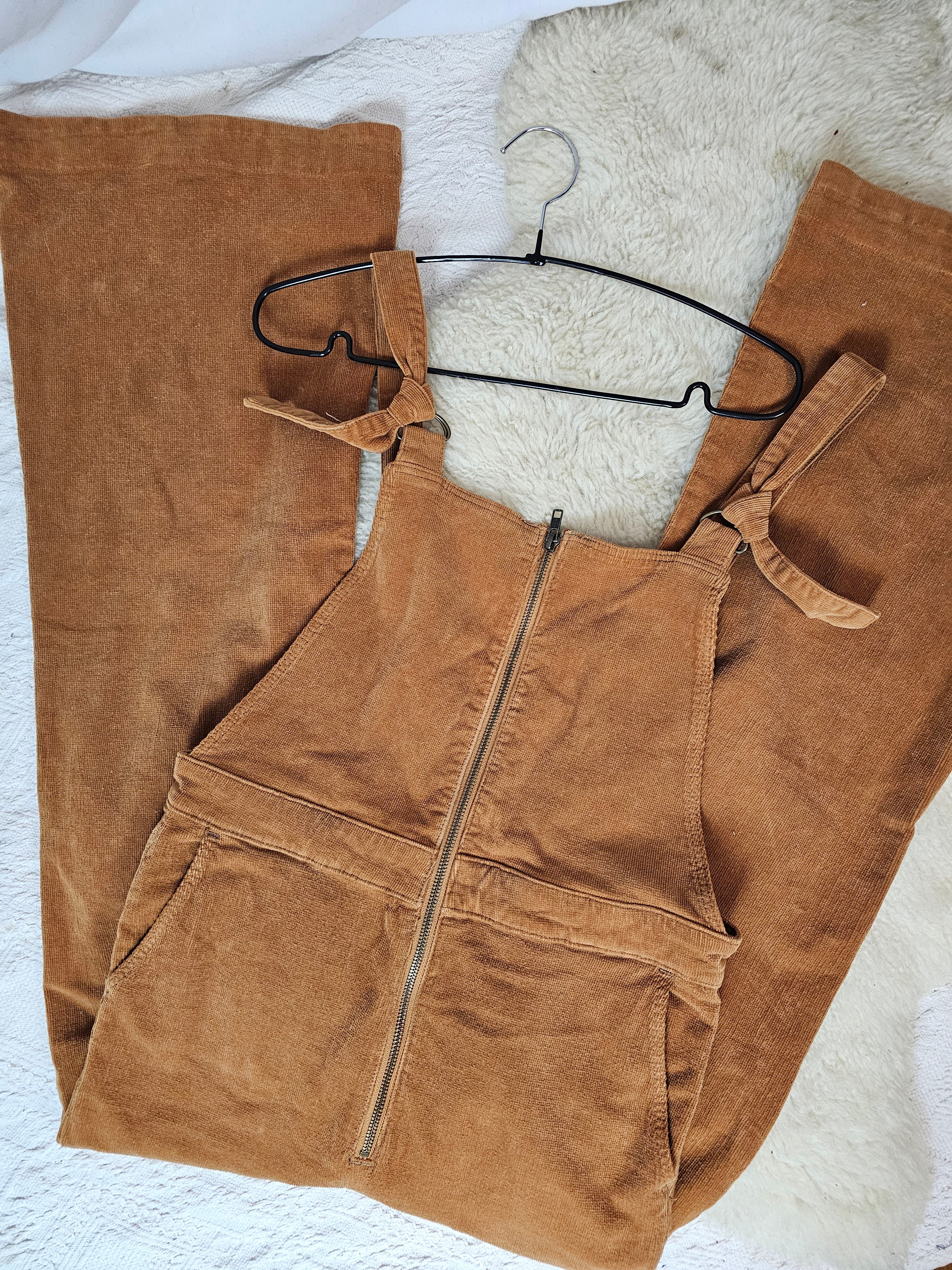 Brown overalls on a hanger against a white background