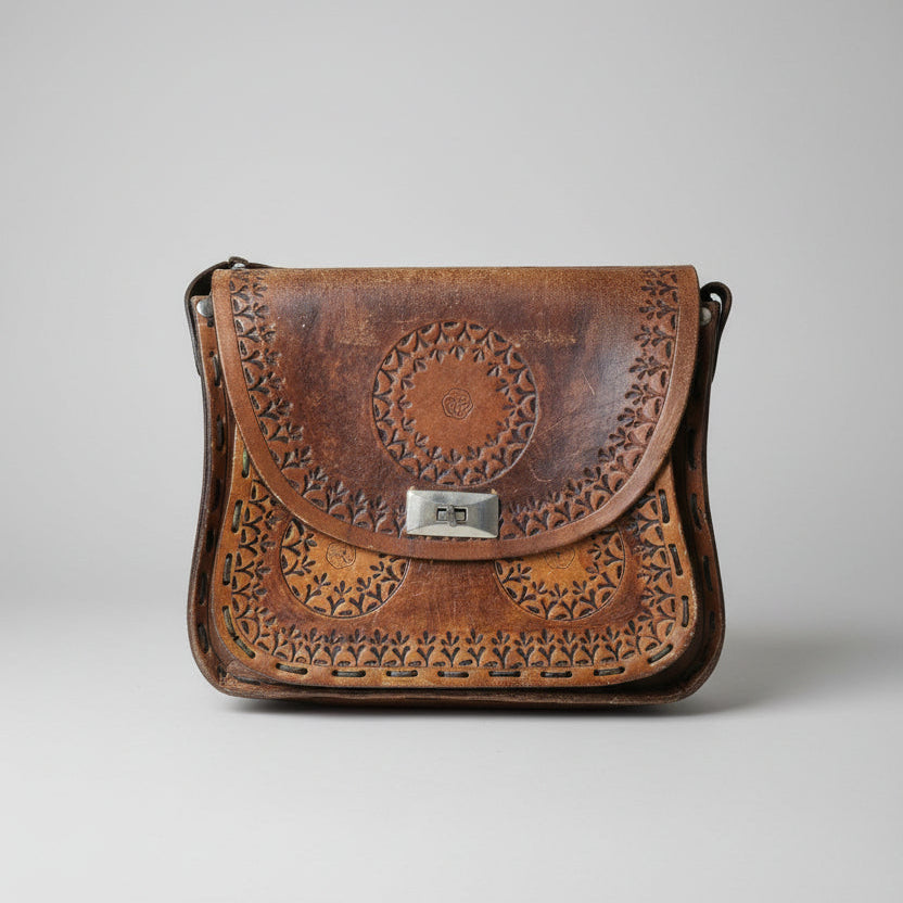 Brown leather bag with intricate cut-out designs on a white background