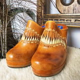 Pair of Vintage Wild Pair Tan Leather Mules – Size 37 with boho fringe and cushioned platform soles, styled on a cozy surface.