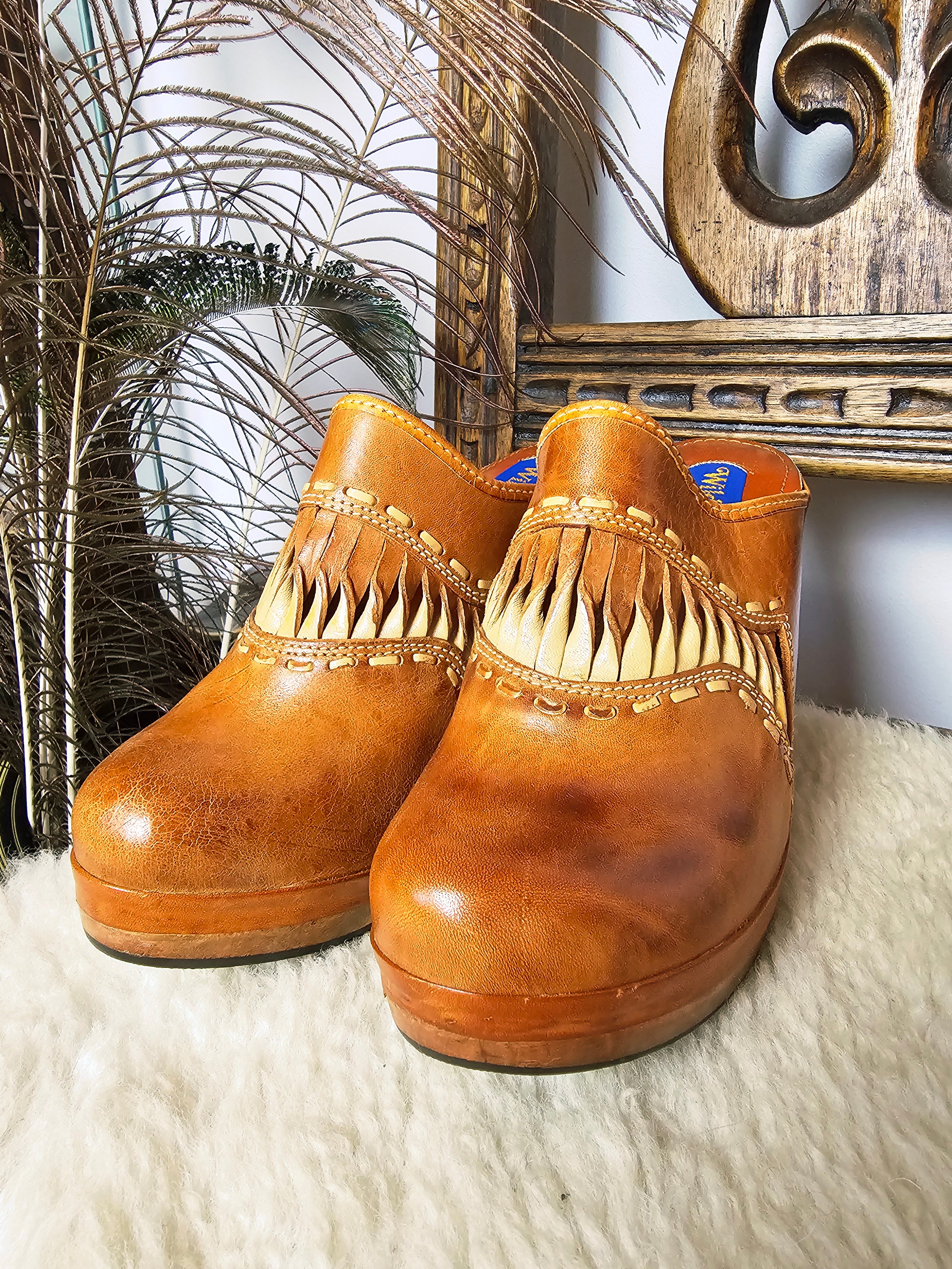 Pair of Vintage Wild Pair Tan Leather Mules – Size 37 with boho fringe and cushioned platform soles, styled on a cozy surface.