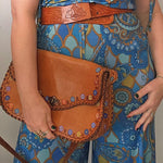 Person wearing a blue patterned outfit holding a brown leather bag.