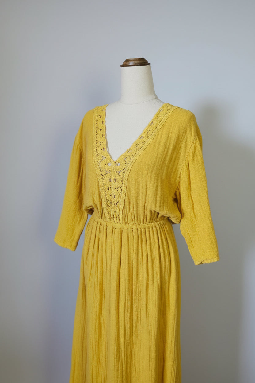 Yellow dress with lace detailing on a mannequin against a neutral background