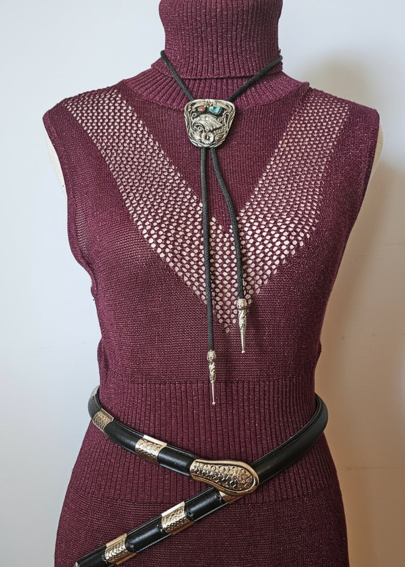 Maroon sweater with decorative brooches on a mannequin against a neutral background
