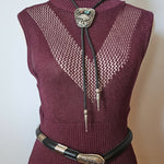 Maroon sweater with decorative brooches on a mannequin against a neutral background
